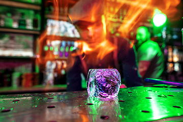 Image showing Close up big melting piece of ice on the bar counter in fireflames on it, preparation for a cocktail