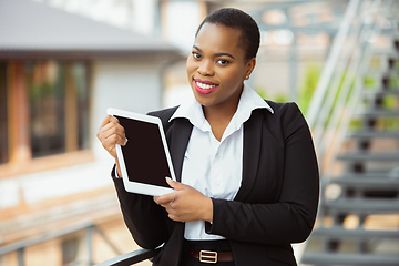 Image showing African-american businesswoman in office attire smiling, looks confident and happy, successful