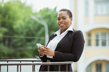 Image showing African-american businesswoman in office attire smiling, looks confident and happy, successful