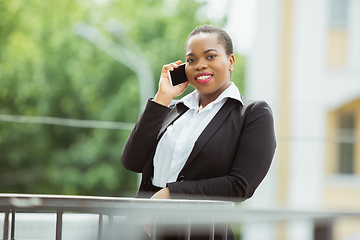 Image showing African-american businesswoman in office attire smiling, looks confident and happy, successful