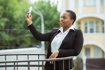 Image showing African-american businesswoman in office attire smiling, looks confident and happy, successful