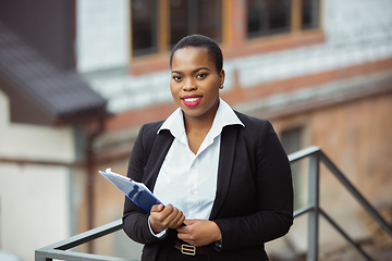 Image showing African-american businesswoman in office attire smiling, looks confident and happy, successful