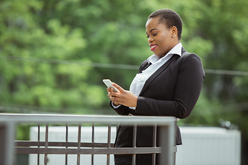 Image showing African-american businesswoman in office attire smiling, looks confident and happy, successful