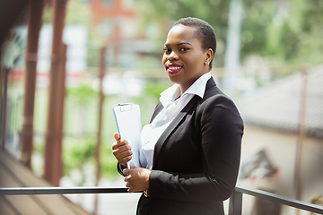 Image showing African-american businesswoman in office attire smiling, looks confident and happy, successful