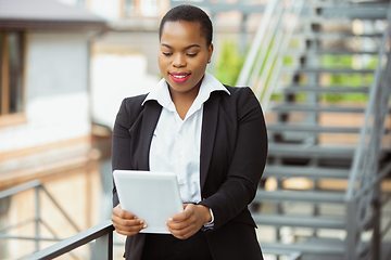 Image showing African-american businesswoman in office attire smiling, looks confident and happy, successful