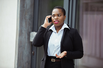 Image showing African-american businesswoman in office attire smiling, looks confident and happy, successful