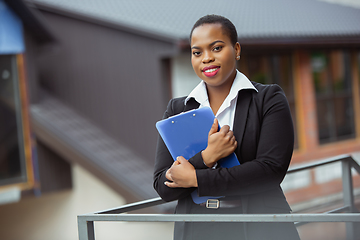 Image showing African-american businesswoman in office attire smiling, looks confident and happy, successful