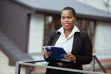 Image showing African-american businesswoman in office attire smiling, looks confident and happy, successful