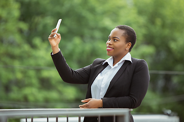 Image showing African-american businesswoman in office attire smiling, looks confident and happy, successful