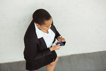 Image showing African-american businesswoman in office attire smiling, looks confident and happy, successful