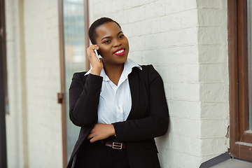 Image showing African-american businesswoman in office attire smiling, looks confident and happy, successful