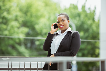 Image showing African-american businesswoman in office attire smiling, looks confident and happy, successful