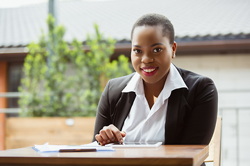 Image showing African-american businesswoman in office attire smiling, looks confident and happy, successful
