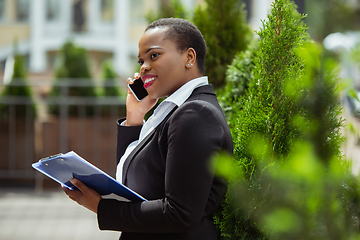 Image showing African-american businesswoman in office attire smiling, looks confident and happy, successful