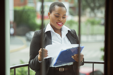 Image showing African-american businesswoman in office attire smiling, looks confident and happy, successful