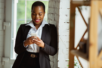 Image showing African-american businesswoman in office attire smiling, looks confident and happy, successful