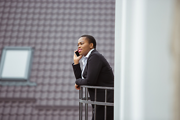 Image showing African-american businesswoman in office attire smiling, looks confident and happy, successful