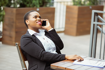 Image showing African-american businesswoman in office attire smiling, looks confident and happy, successful