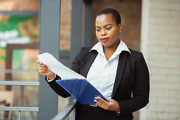 Image showing African-american businesswoman in office attire smiling, looks confident and happy, successful