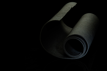 Image showing Professional sport equipment isolated on black studio background. Exercise mat.