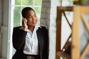 Image showing African-american businesswoman in office attire smiling, looks confident and happy, successful