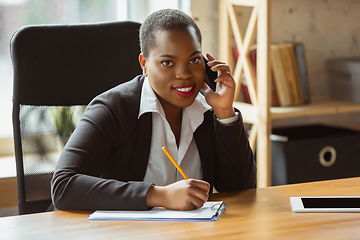 Image showing African-american businesswoman in office attire smiling, looks confident and happy, successful