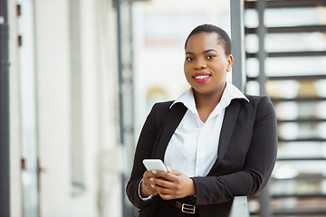 Image showing African-american businesswoman in office attire smiling, looks confident and happy, successful