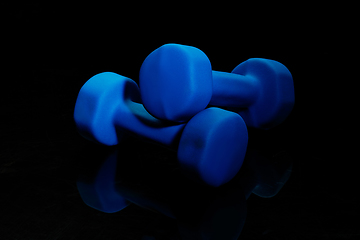 Image showing Professional sport equipment isolated on black studio background. Blue gym weights.