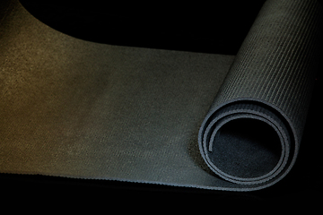 Image showing Professional sport equipment isolated on black studio background. Exercise mat.