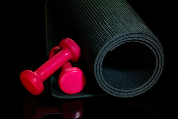 Image showing Professional sport equipment isolated on black studio background. Exercise mat and weights.