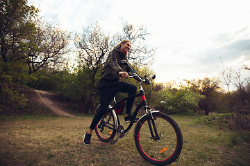 Image showing Young man having fun near countryside park, riding bike, traveling at spring day