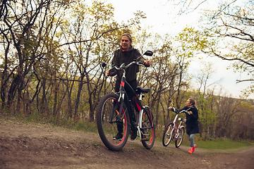 Image showing Best friends having fun near countryside park, riding bikes, spending time healthy