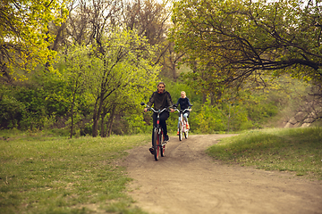 Image showing Best friends having fun near countryside park, riding bikes, spending time healthy