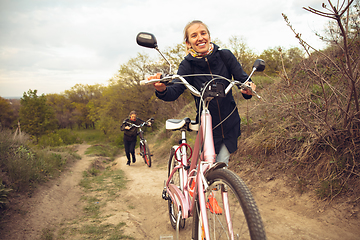 Image showing Best friends having fun near countryside park, riding bikes, spending time healthy