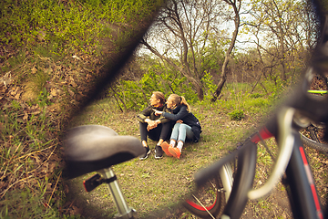 Image showing Best friends having fun near countryside park, resting after riding bikes, spending time together, sitting on the grass. Reflection in mirror.