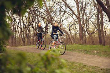 Image showing Best friends having fun near countryside park, riding bikes, spending time healthy