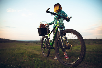 Image showing Young woman having fun near countryside park, riding bike, traveling with companion spaniel dog