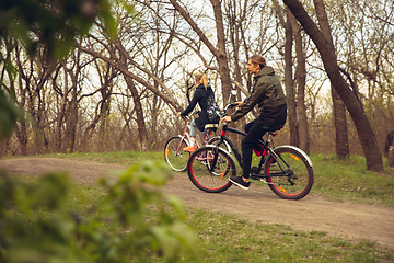 Image showing Best friends having fun near countryside park, riding bikes, spending time healthy