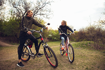 Image showing Best friends having fun near countryside park, riding bikes, spending time healthy