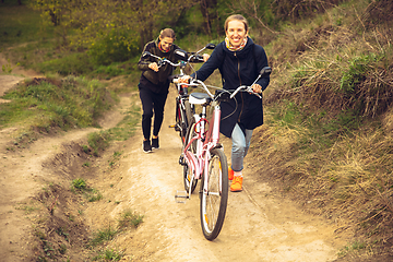 Image showing Best friends having fun near countryside park, riding bikes, spending time healthy