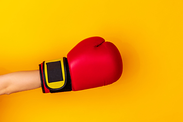 Image showing Hand in boxing red glove isolated on yellow studio background with copyspace.