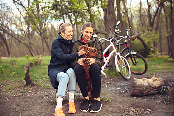 Image showing Best friends having fun near countryside park, resting after riding bikes, spending time together, sitting on the grass