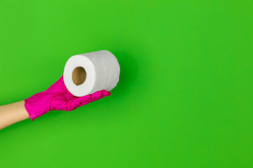 Image showing Hand in pink rubber glove with toilet paper isolated on green studio background with copyspace.