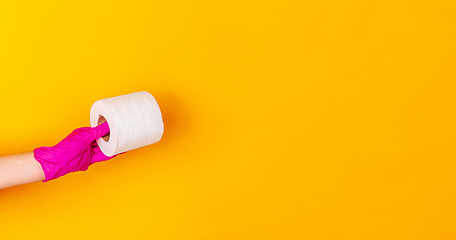 Image showing Hand in pink rubber glove holding toilet paper isolated on yellow studio background with copyspace. Flyer.