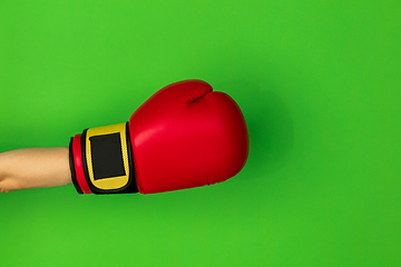 Image showing Hand in boxing red glove isolated on green studio background with copyspace.