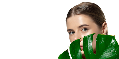 Image showing Organic. Close up of beautiful young woman with green leaves over white background. Cosmetics and makeup, natural and eco treatment, skin care. Flyer with copyspace.