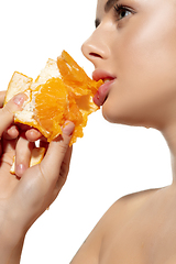 Image showing Energy. Close up of beautiful young woman biting juicy orange over white background. Cosmetics and makeup, natural and eco treatment, skin care.