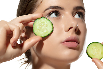 Image showing Freshness. Close up of beautiful young woman with cucumber\'s slices on her face on white background. Cosmetics and makeup, natural and eco treatment, skin care.