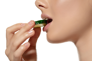 Image showing Freshness. Close up of beautiful young woman biting cucumber\'s slice over white background. Cosmetics and makeup, natural and eco treatment, skin care.
