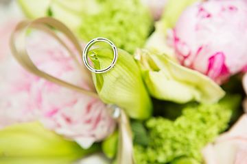 Image showing wedding rings lie on a beautiful bouquet as bridal accessories